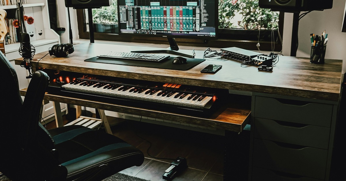Arturia KeyLab Essential MIDI controller keyboard on a desk in a home recording studio with headphones nearby