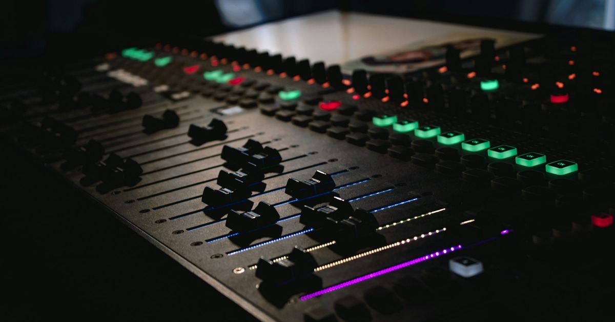 Compressor controls on a dark studio mixing desk with faders and knobs