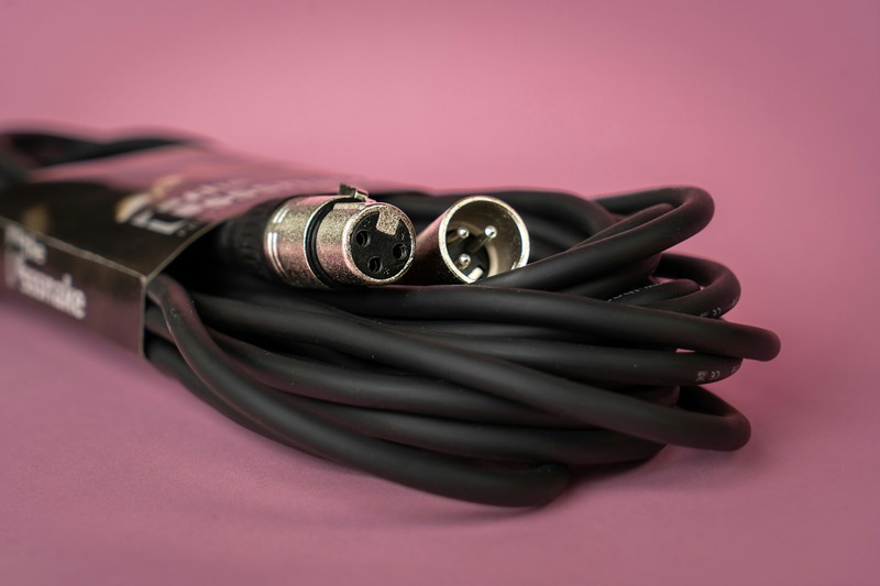 Three black XLR audio cables coiled on a floor