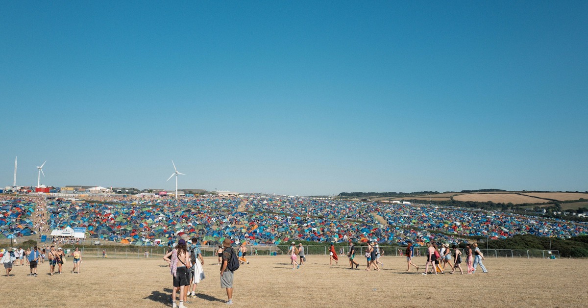 A festival campsite with a dome tent and a canopy set up on grass