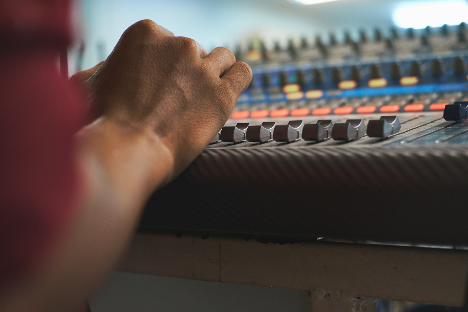Close up of hands adjusting faders on an analog mixing console in a recording studio