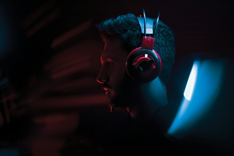 A vocalist wearing closed-back headphones in front of a microphone in a recording studio