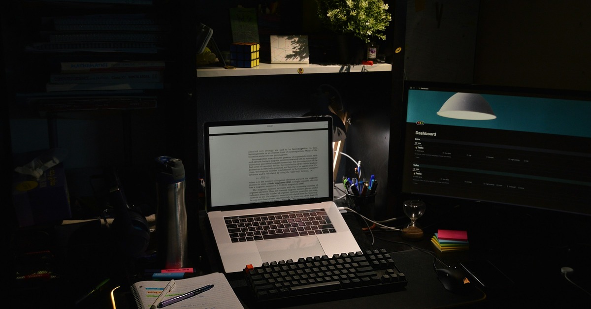 A DJ controller and laptop set up on a budget folding table with black fabric covering the front