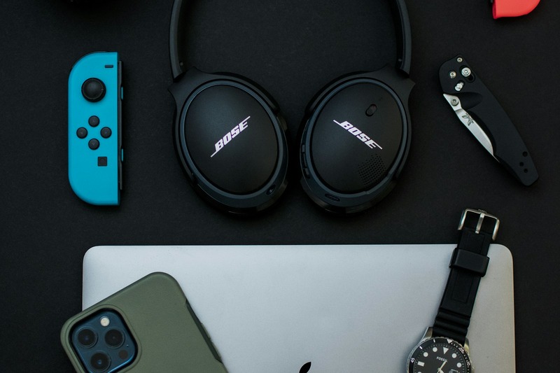 An open hard carrying case holding DJ headphones with replacement earpads and a coiled cable beside a mixer