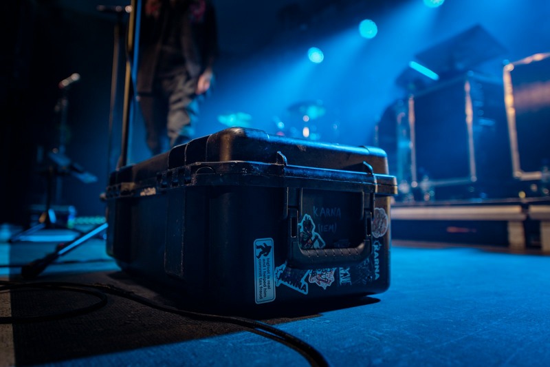 A black DJ rolling case with telescopic handle and wheels positioned on a stage
