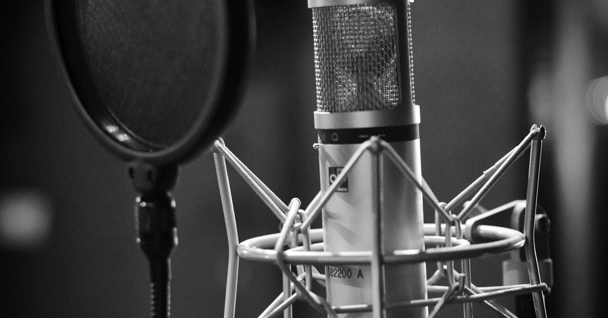 A home recording studio setup with a microphone, audio interface, and headphones on a desk