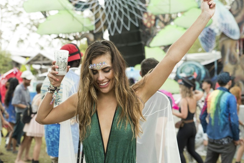 A person drinking water from a hydration bladder tube at a festival