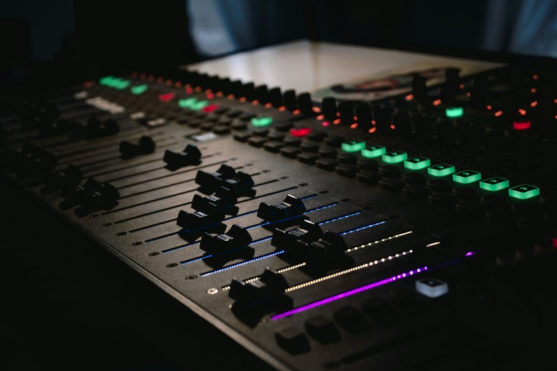 An audio engineer adjusting controls on a mixing console in a mastering studio