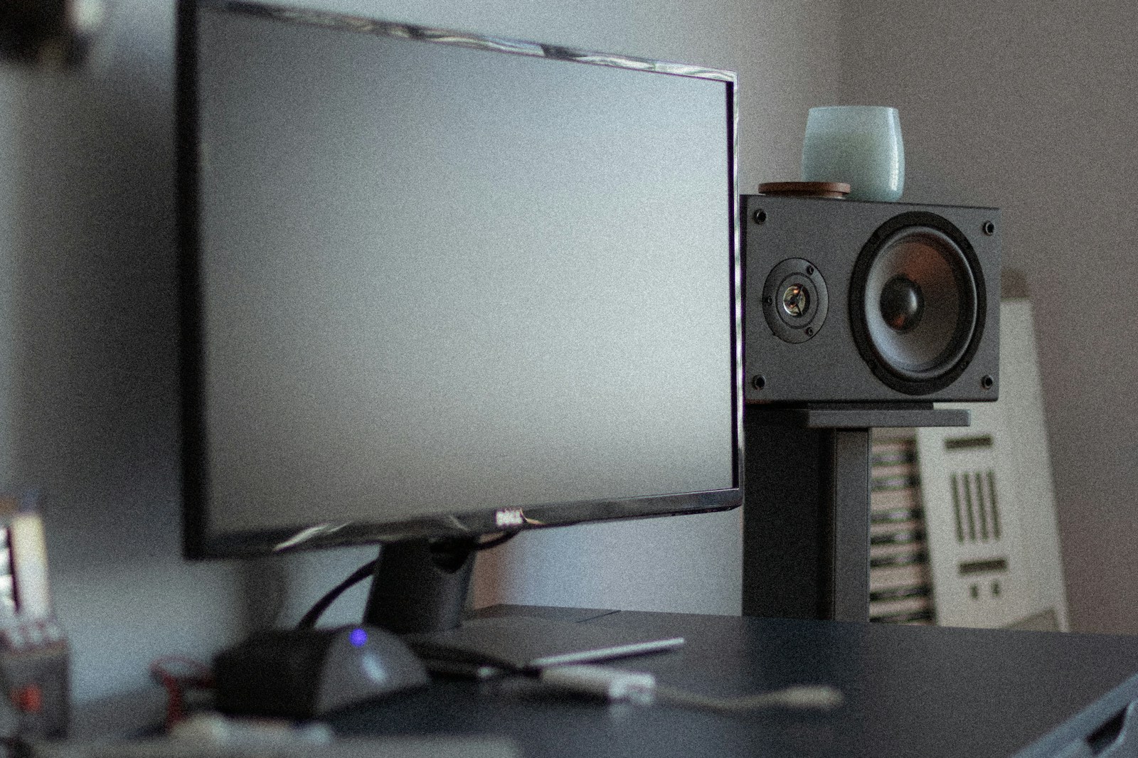 modern home studio desk with high-end studio monitors on stands, acoustic panels on walls, and warm ambient lighting
