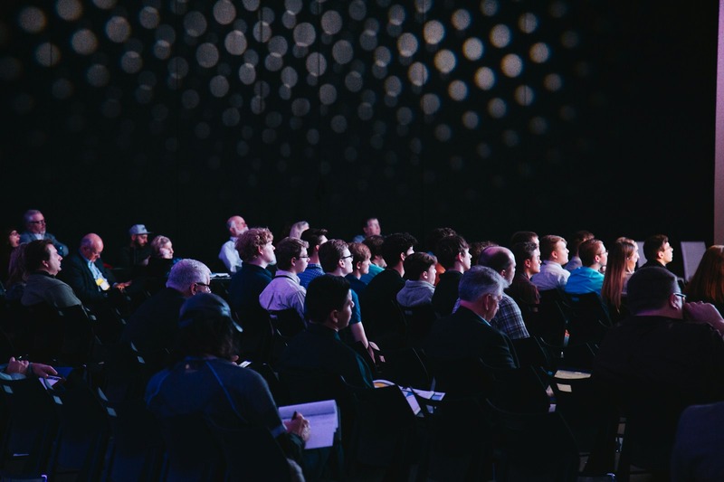 Attendees at a music conference workshop panel listening and taking notes