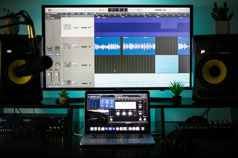 A portable audio interface placed next to a MacBook Air with headphones and USB cable