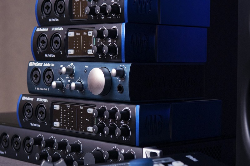 A rack-mounted professional audio interface with multiple preamps and cables in a recording studio