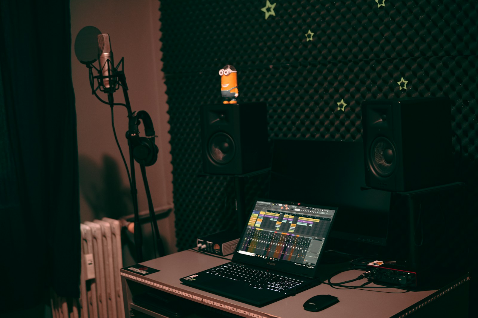 Recording microphone with a pop filter set up in a home studio with headphones nearby