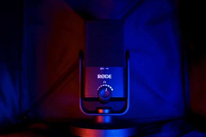 Rode NT1-A condenser microphone connected via XLR cable to an audio interface, with a laptop showing a DAW session open.