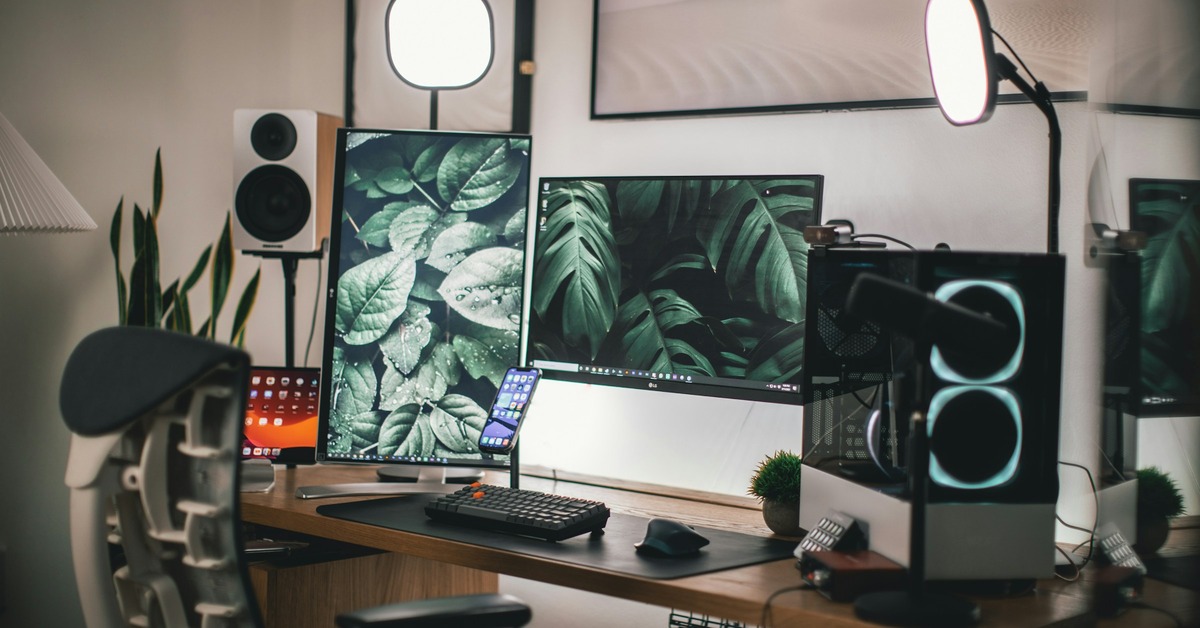 Studio desk setup in a small room with monitors keyboard and chair