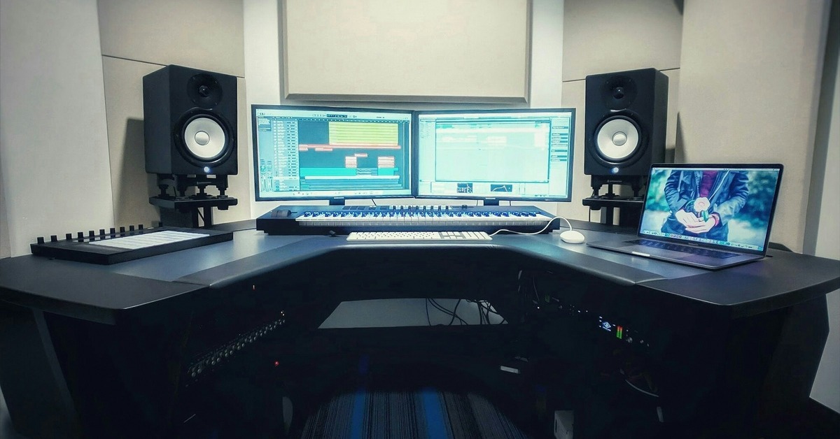 Studio monitors on stands in a room with acoustic treatment panels on the walls