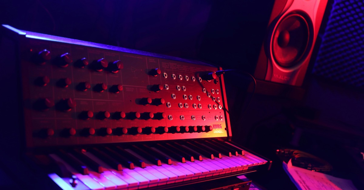 Studio desk with a laptop showing a synth plugin interface, headphones, and MIDI controller for creating ambient textures